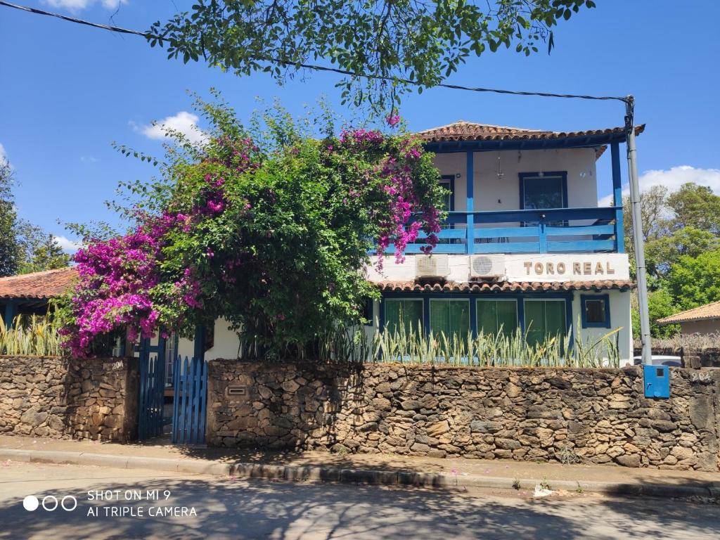een gebouw met een stenen muur en paarse bloemen bij Pousada Toro Real in Tiradentes