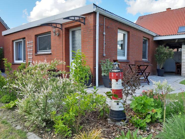 una casa con una boca de incendios roja y blanca en un jardín en Ferienwohnung Familie Kluge, en Jemgum