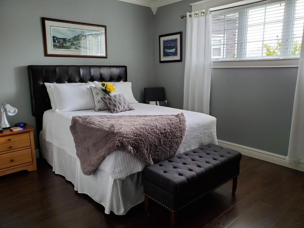 a bedroom with a large bed with a black foot stool at The Blue Jay Nest in Topsail