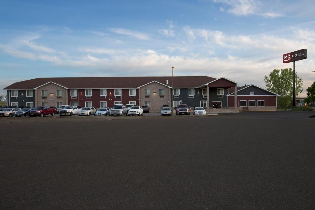 un gran edificio con coches estacionados en un estacionamiento en Miles City Hotel, en Miles City