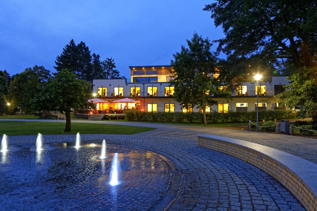 ein Gebäude mit einem Brunnen vor einem Gebäude in der Unterkunft Hotel am Kurpark in Zinnowitz