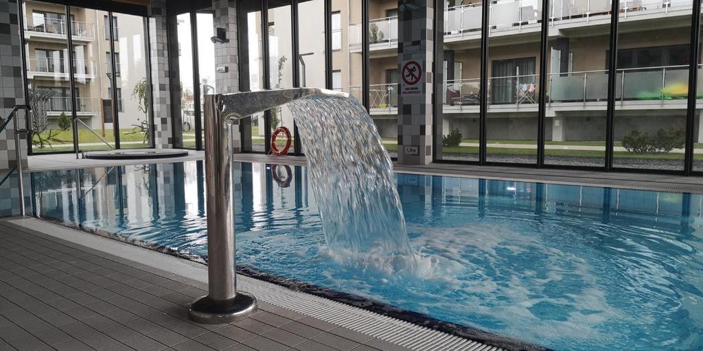 a fountain in a swimming pool in a building at Apartamenty Relaks & Spa Pięć Mórz in Sianozety