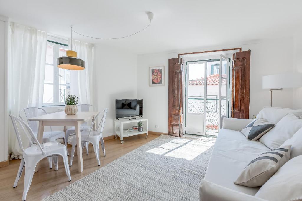ein weißes Wohnzimmer mit einem weißen Sofa und einem Tisch in der Unterkunft Light Filled Typical Apartment at Alfama, By TimeCooler in Lissabon