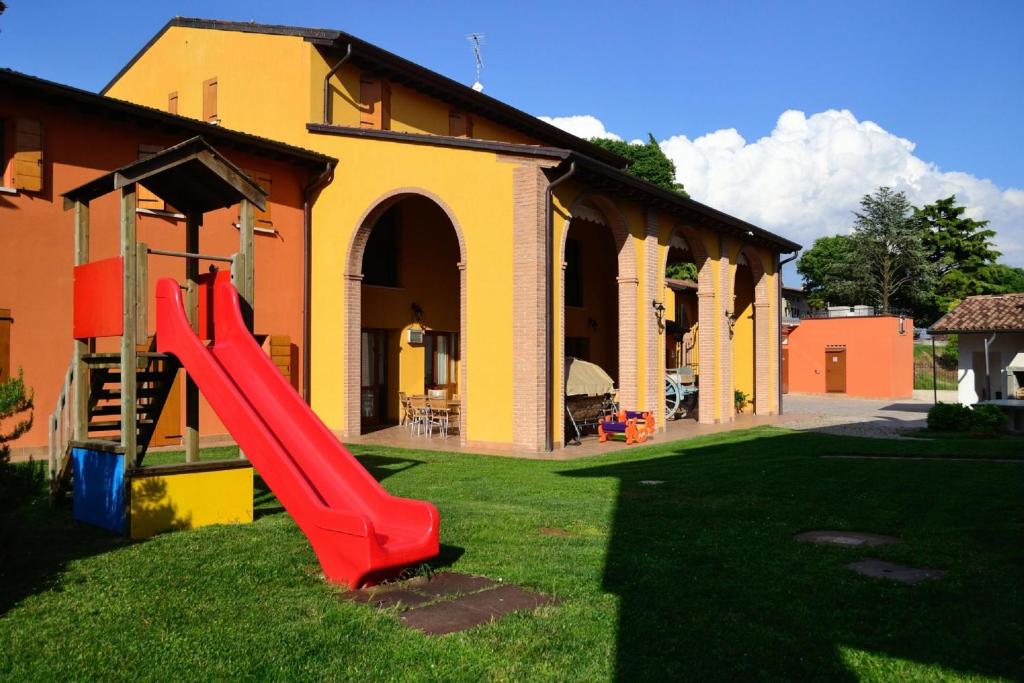 a playground in front of a building with a red slide at Agriturismo Bortolino in Volta Mantovana