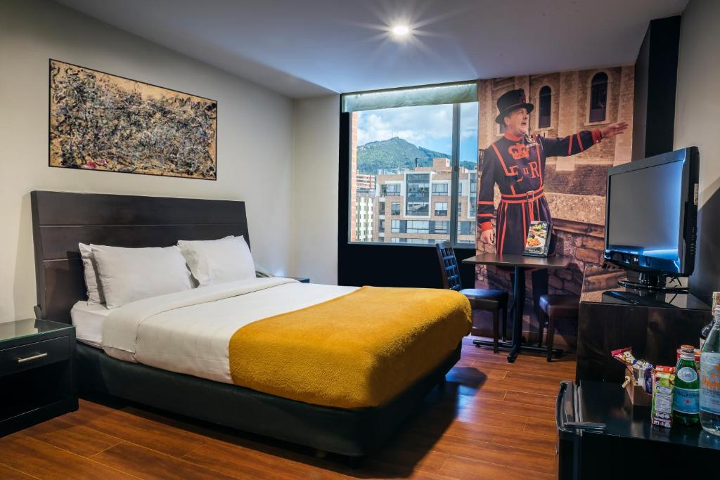 a bedroom with a bed, a desk and a painting on the wall at Hotel Santa Barbara Real in Bogotá