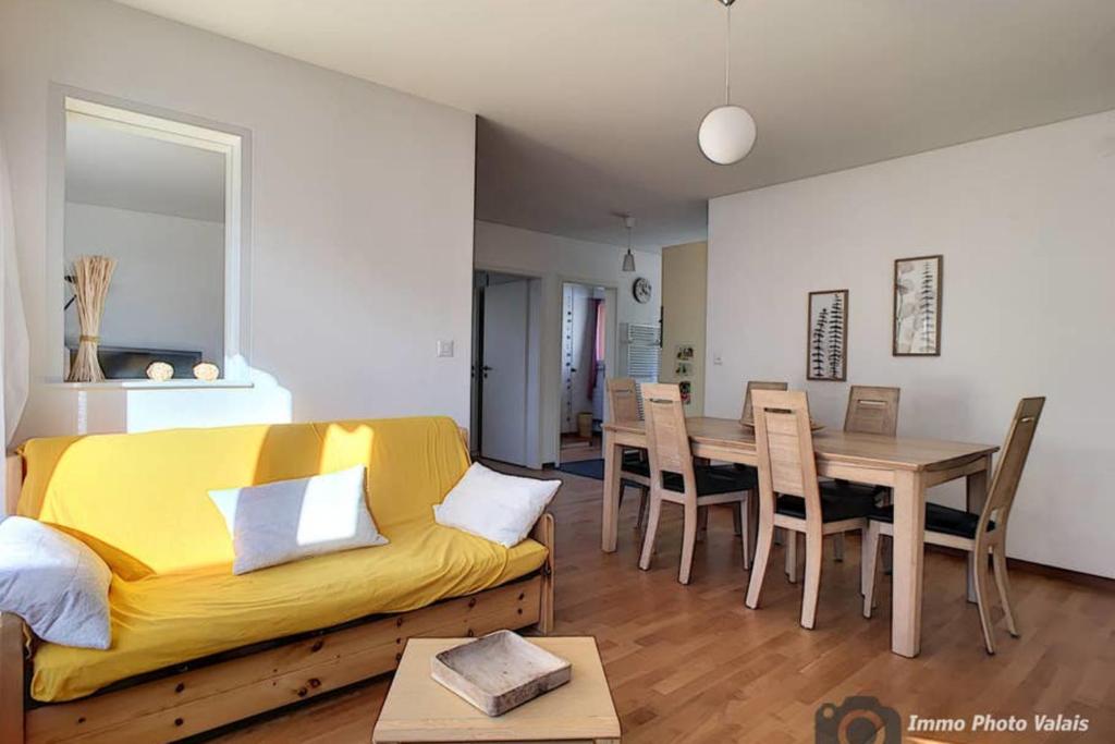 a living room with a yellow couch and a table at Marie-Rose 8 in Bagnes