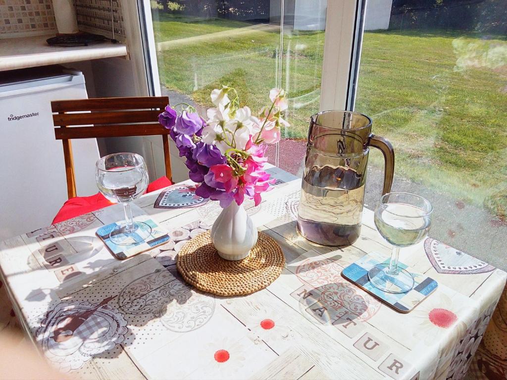 a table with a vase of flowers and glasses on it at Chalet for two - Dartmouth in Dartmouth