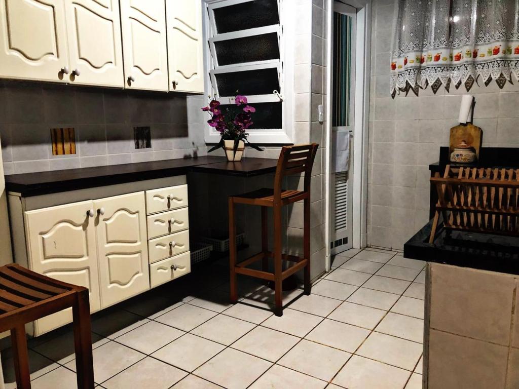 een keuken met witte kasten en een tafel en stoelen bij Apartamento frente ao mar Pitangueiras in Guarujá