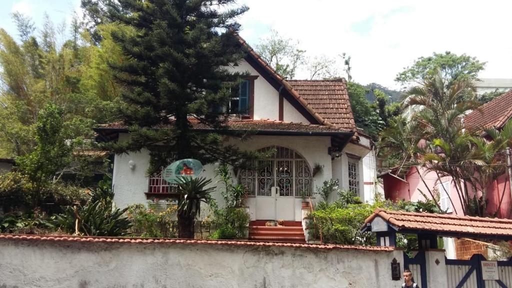 ein weißes Haus mit einem Zaun davor in der Unterkunft Hostel Petrópolis in Petrópolis