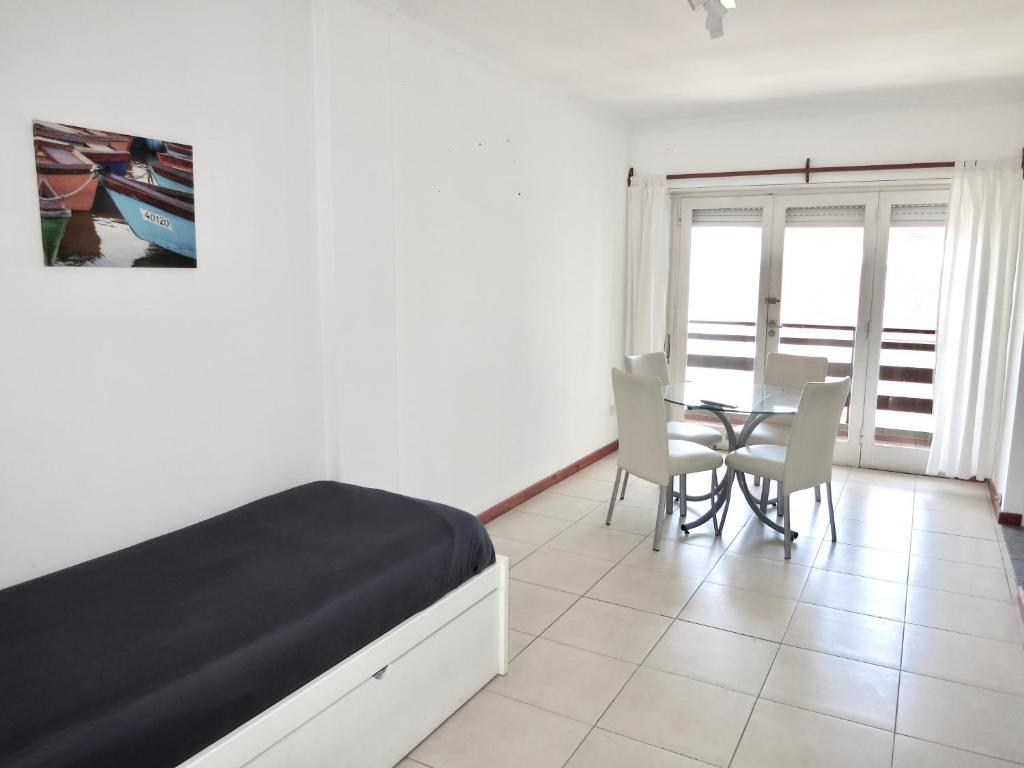 1 dormitorio con 1 cama, mesa y sillas en Cabo Corrientes Center en Mar del Plata