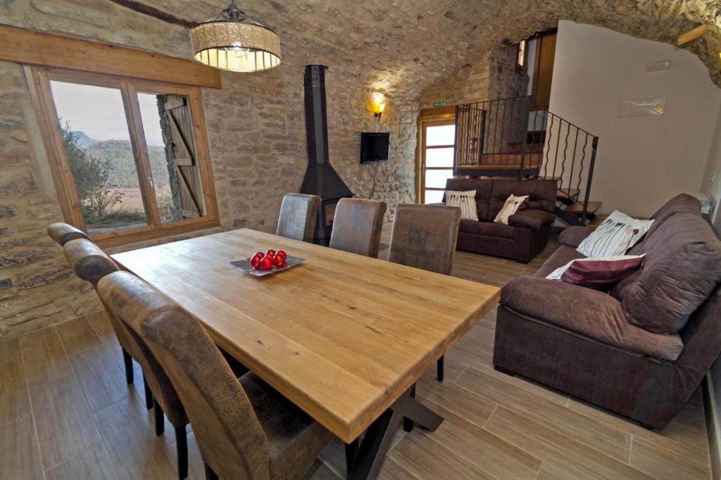 uma sala de estar com uma mesa de madeira e cadeiras em La Bodega de Puy em Graus