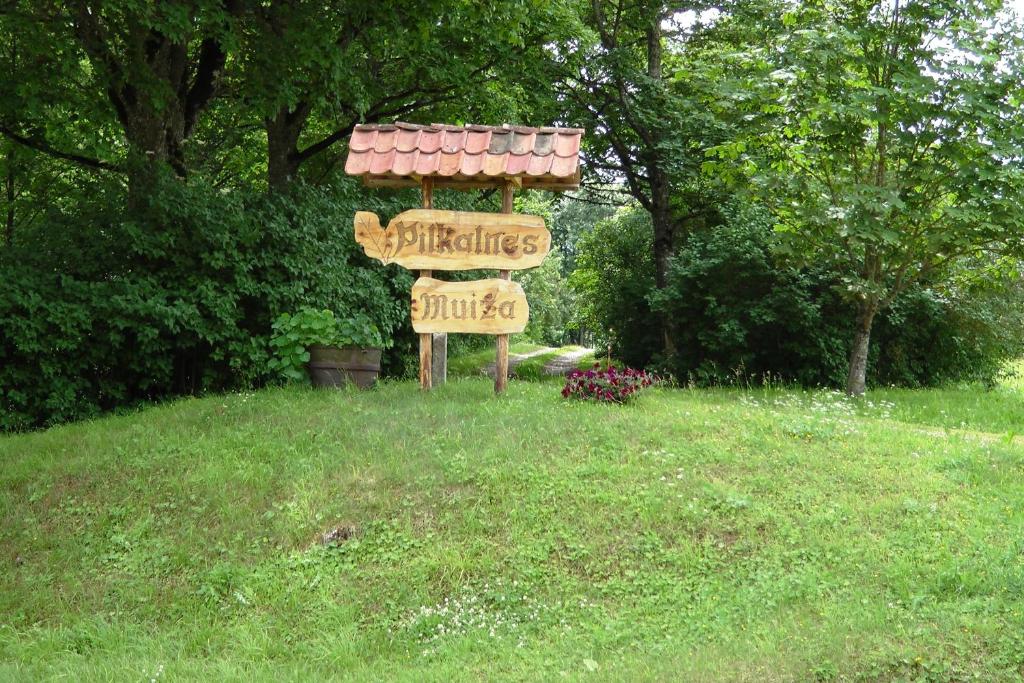 a sign in the middle of a grass field at Pilkalnes muiža in Nereta