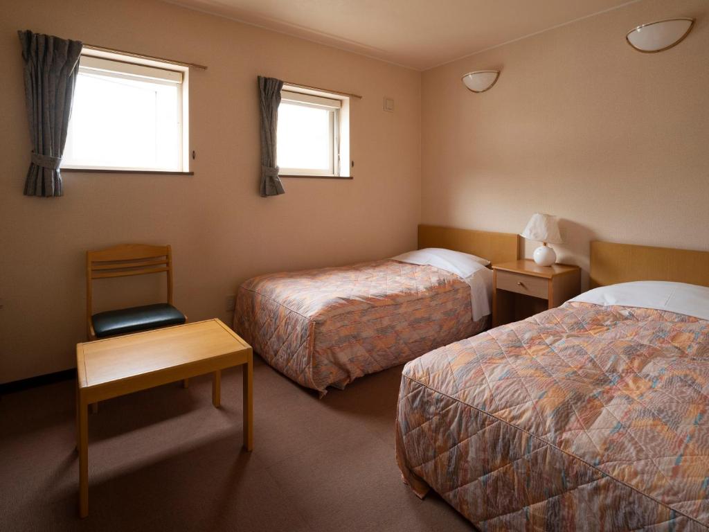 a hotel room with two beds and two windows at Shimanoyado Rebunshiri in Rebun