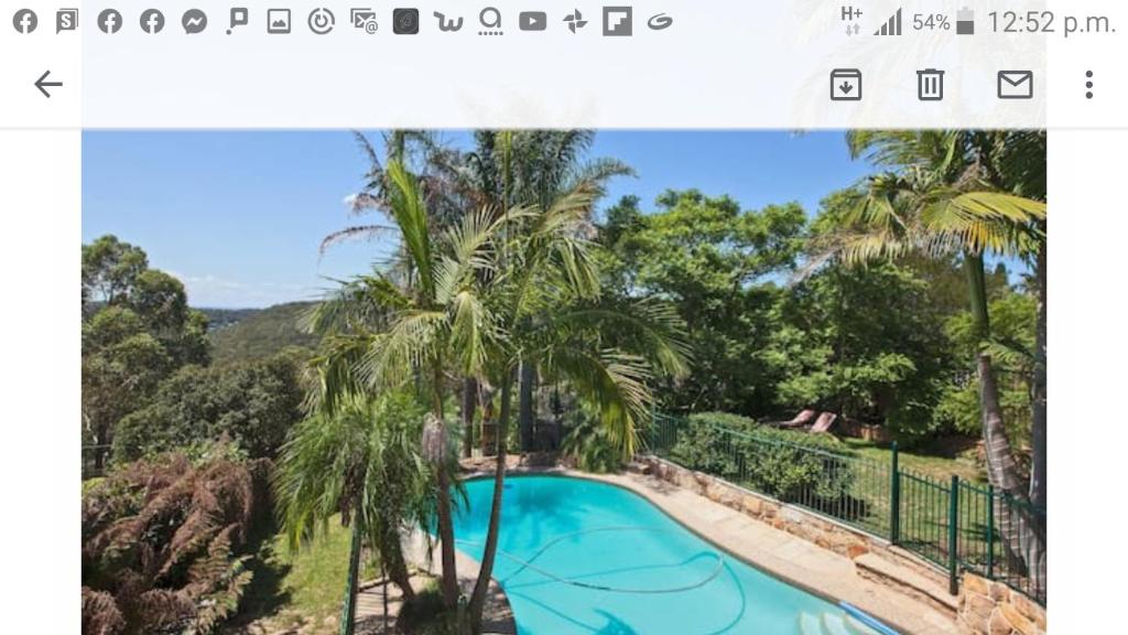 a screenshot of a photo of a swimming pool with palm trees at Serenity in Sutherland