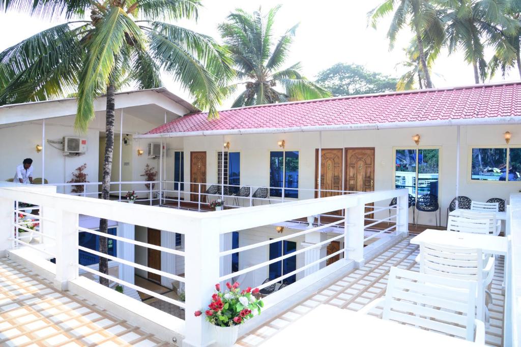 ein Haus mit einem Balkon mit weißen Stühlen und Palmen in der Unterkunft Hotel My Soulmate, Palolem Beach in Palolem