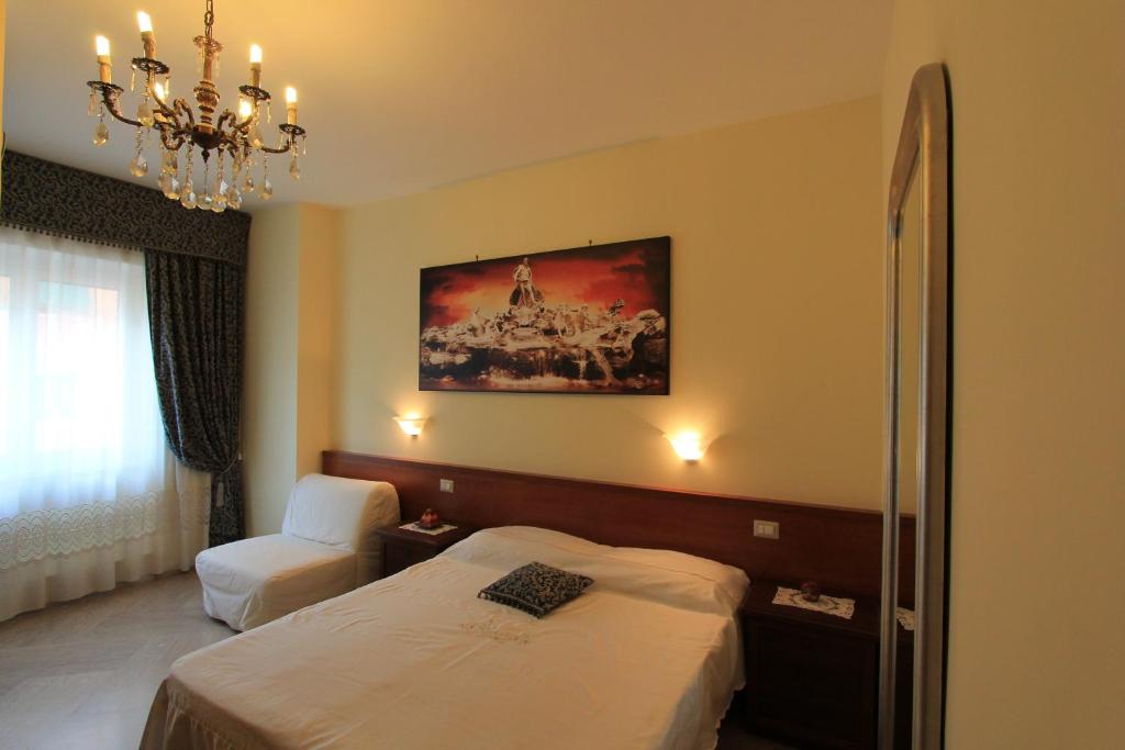 ローマにあるLe Terrazze Del Vaticanoのベッドとシャンデリアが備わるホテルルームです。
