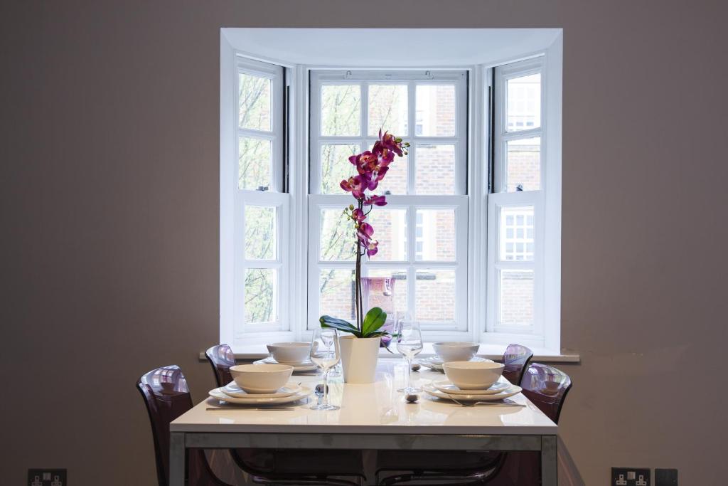 a dining room table with a vase of flowers on it at Urban Living's - The Huxley in Oxford