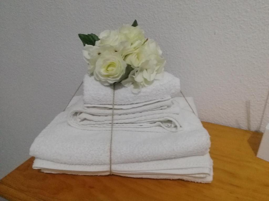 einen Stapel Handtücher mit einem Blumenstrauß drauf in der Unterkunft TRIANA PUREZA 12-14 in Sevilla