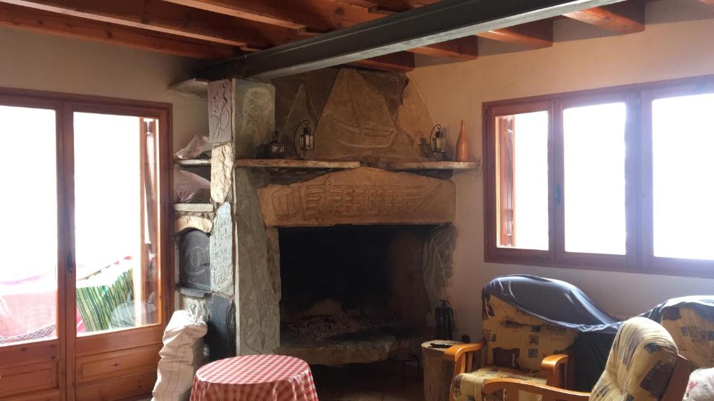 a living room with a fireplace and two windows at Casa Pirineu in Esterri de Cardós