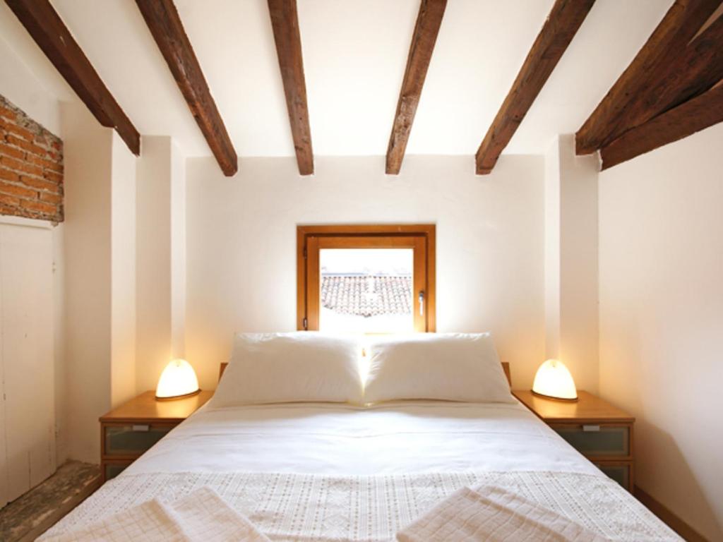 1 dormitorio con 1 cama blanca y 2 lámparas en Mercalli II, en Milán