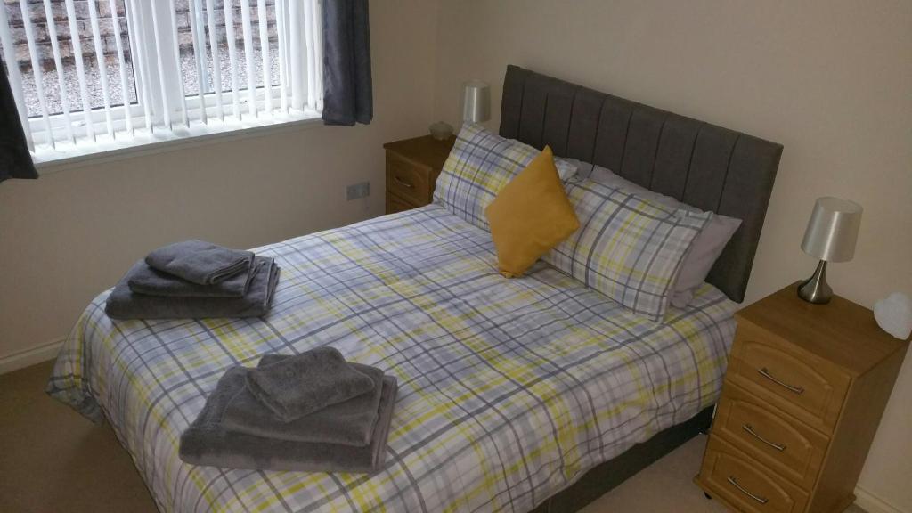 1 dormitorio con 1 cama con toallas en Lerwick Garden Apartment en Inverness