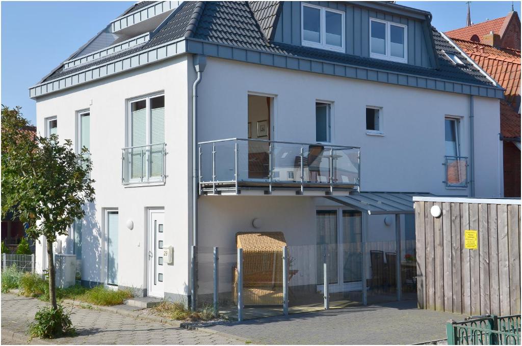 a white house with a balcony and a fence at Jann-Berghaus-Straße 29 in Norderney