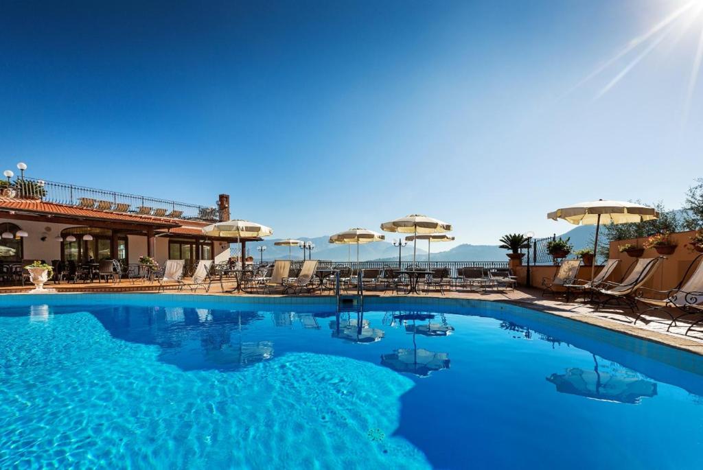 a large swimming pool with chairs and umbrellas at Hotel La Vue d'Or in Sorrento