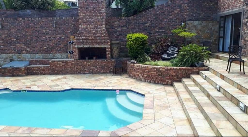 a swimming pool in a yard with a brick wall at Blue Sea Guest House in East London