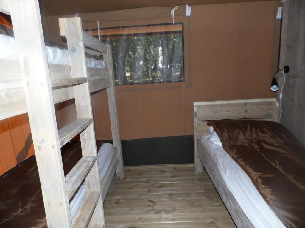 a bedroom with two bunk beds and a window at Camping Mille Étoiles in Labastide-de-Virac