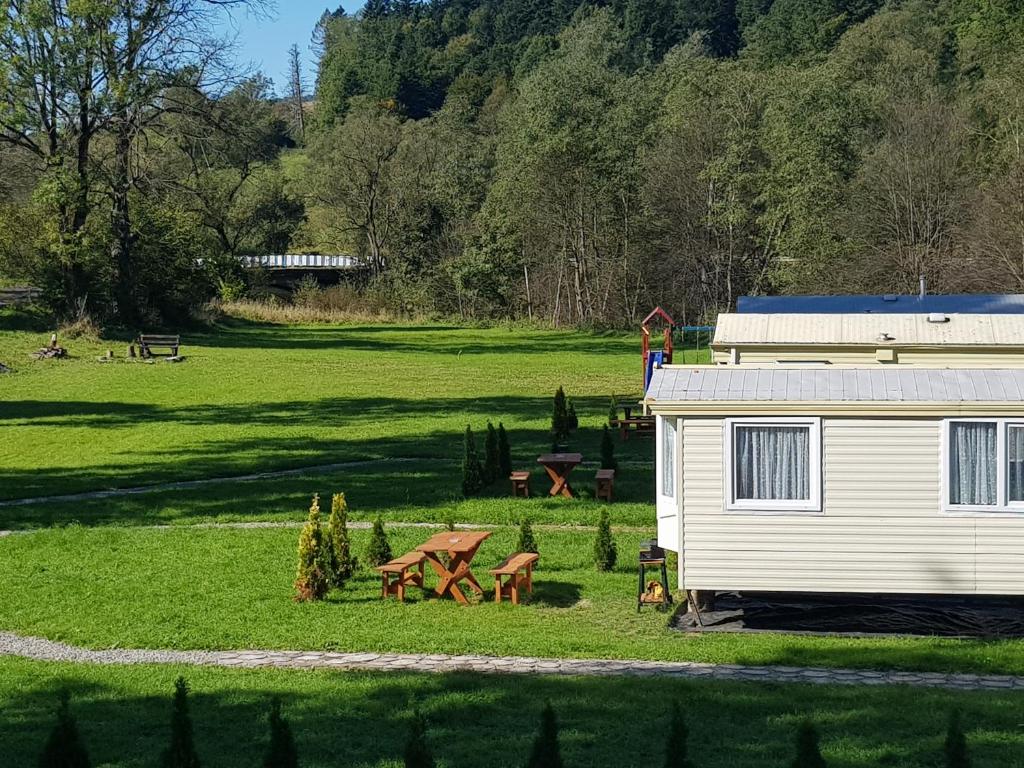 a white trailer with a picnic table in a field at Domki u Brzeginy in Ustrzyki Dolne