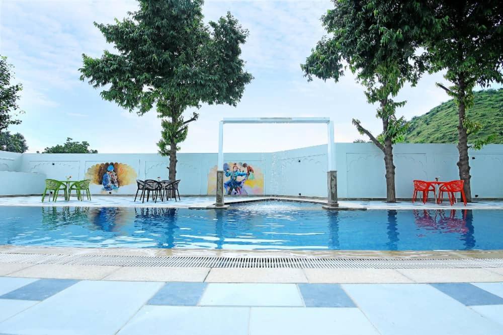 una piscina con mesas y sillas junto a una pared en Dasmaya resort, en Udaipur