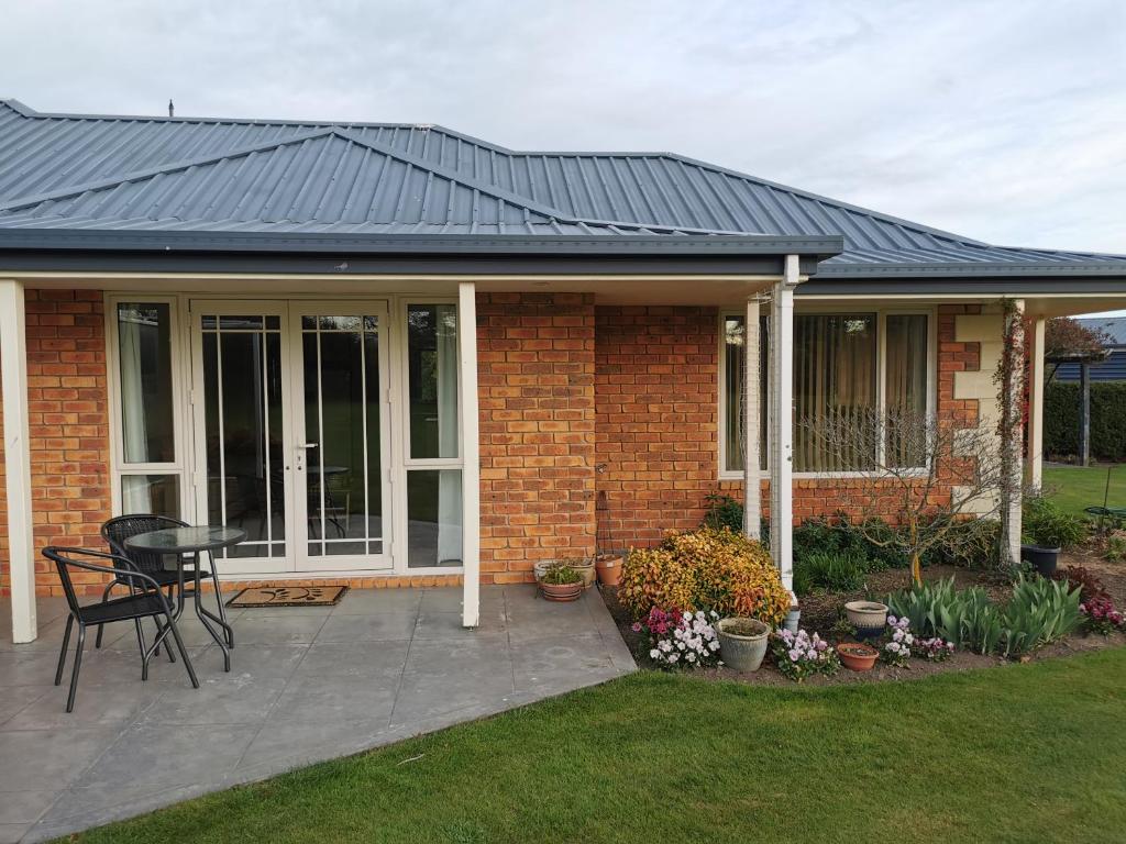 a brick house with a black roof and a patio at Mattanna Apartment in Rangiora