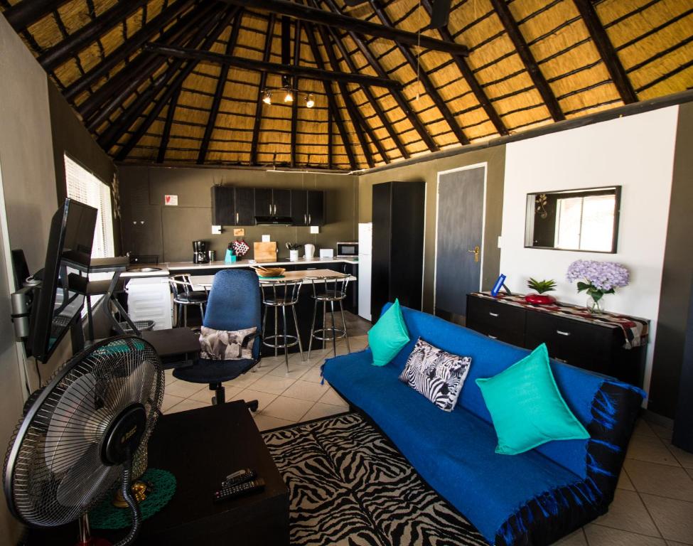 sala de estar con sofá azul y cocina en John-Lou's Studio Flat en Windhoek