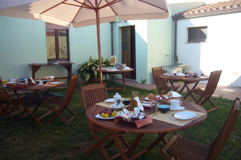 grupa stołów z krzesłami i parasolem w obiekcie Lanita B&B w mieście Cabras