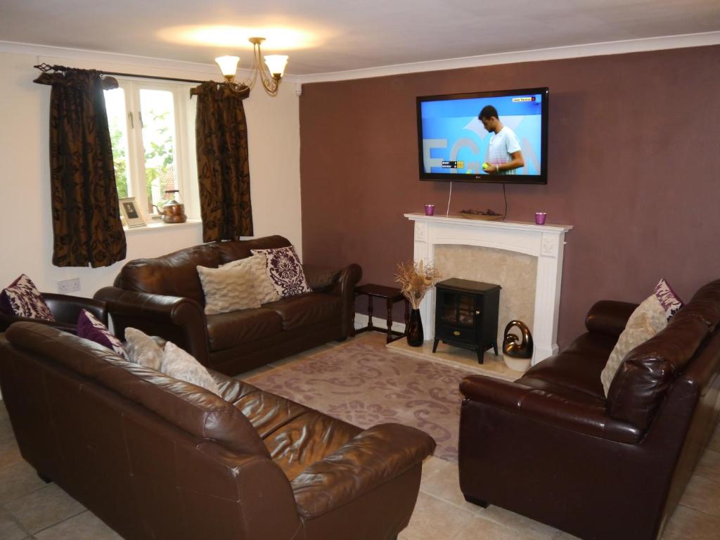 a living room with leather furniture and a tv on a wall at Falstaff Cottage for up to 5, Stratford upon Avon in Stratford-upon-Avon