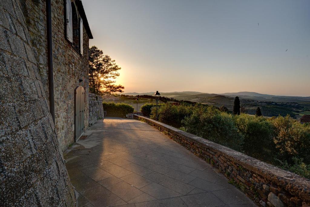 a stone path next to a building with the sunset in the background at Torre dei Serviti in Casole dʼElsa