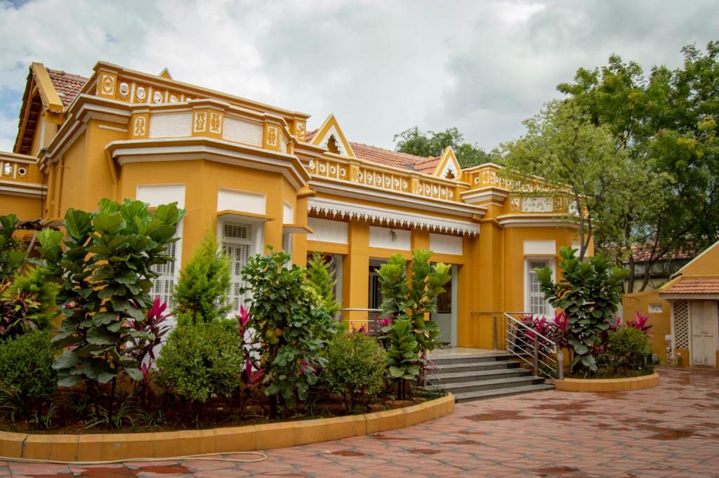Una casa amarilla con plantas delante. en Roambay en Mysore