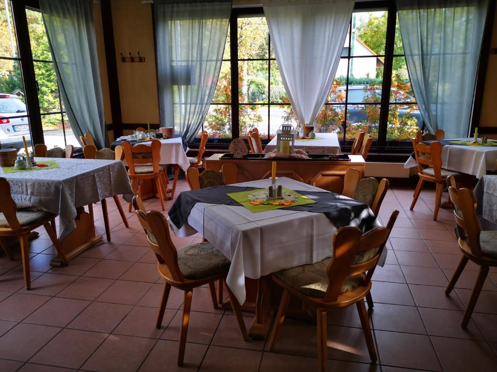 a dining room with tables and chairs and windows at Casa Mia Pension am Mailandsberg - Klima in Lutherstadt Wittenberg
