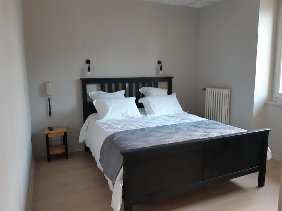 Un dormitorio con una gran cama negra con almohadas blancas en LE HAYLTON, en Anglefort