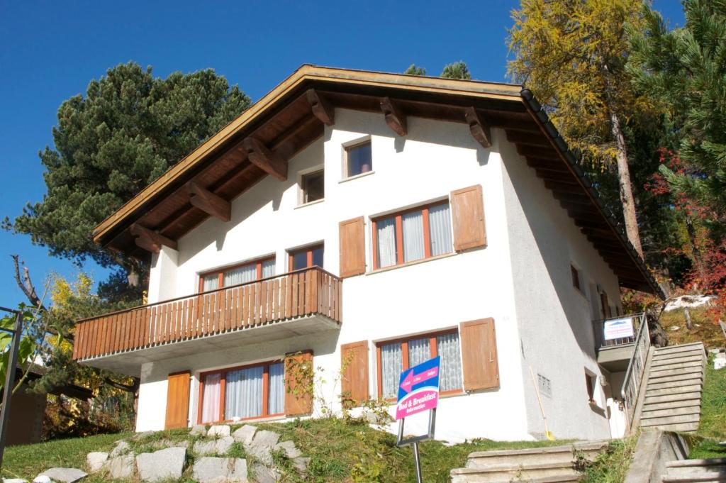 a white house with a balcony on a hill at B&B St Moritz in St. Moritz