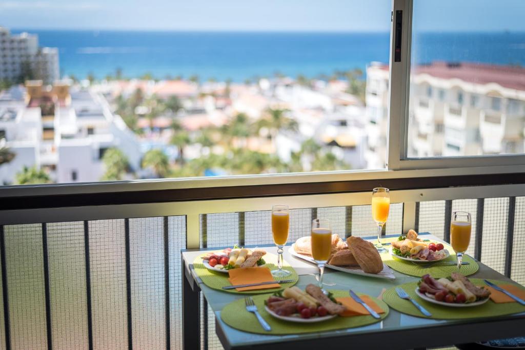 una mesa con dos platos de comida y vasos de zumo de naranja en 928 Amazing View El Dorado, en Playa de las Américas