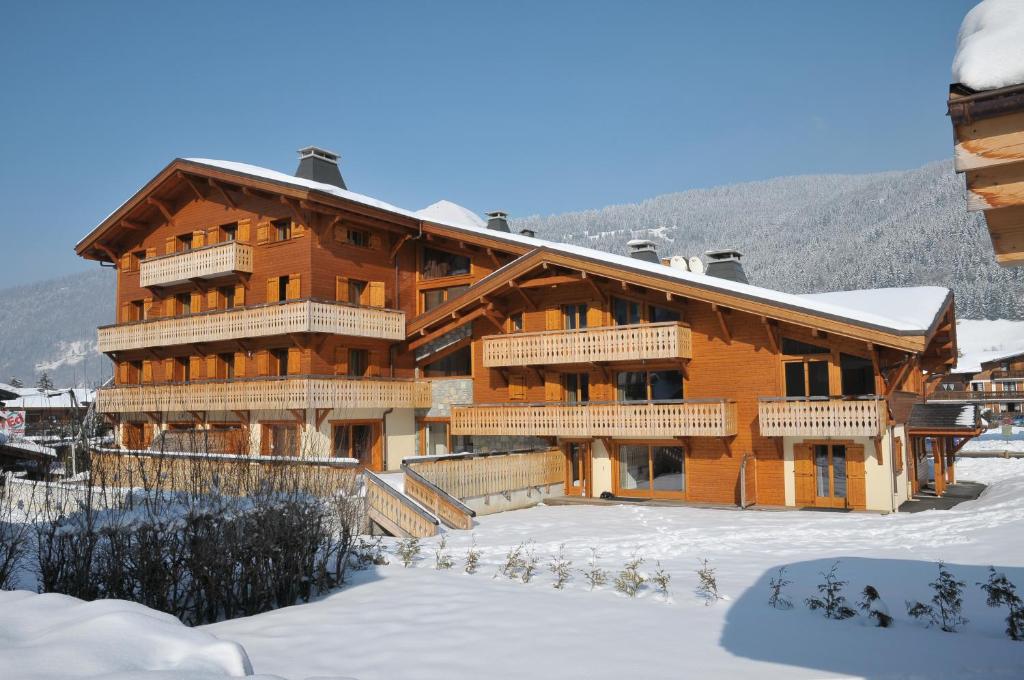 um grande edifício de madeira com neve no chão em Aiglon Morzine em Morzine