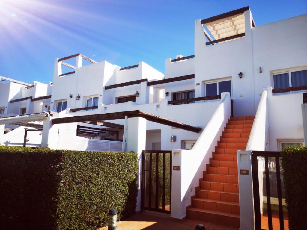 a white building with stairs and bushes at Condado de Alhama Jardin 13 Appartement 1506 in El Romero