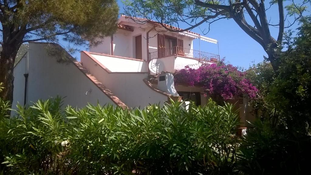 uma casa branca com varanda e flores roxas em B&B Vacanza Facile em Costa Rei