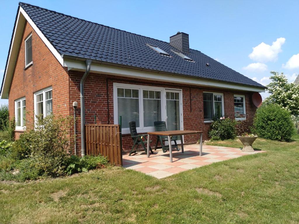 a brick house with a patio with a table at Gästehaus Tiedemann in Borsfleth