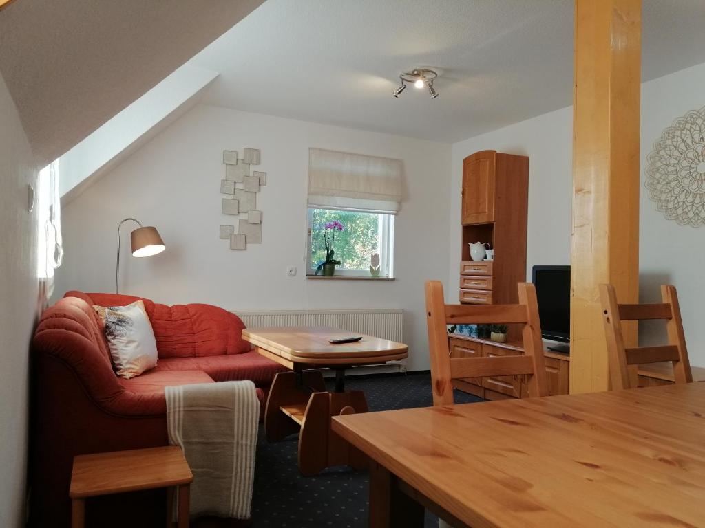 ein Wohnzimmer mit einem roten Sofa und einem Tisch in der Unterkunft Ferienwohnung Wilhelm in Springstille