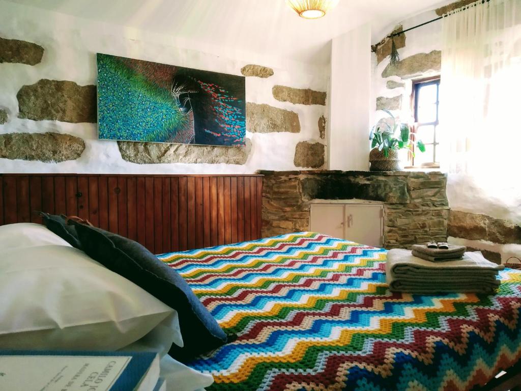 ein Schlafzimmer mit einem Bett mit einem bunten Teppich darauf in der Unterkunft Lago da Garça Guesthouse in São Pedro do Sul