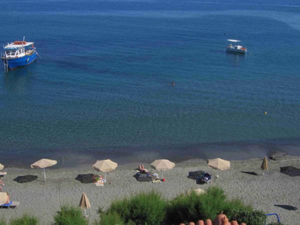 a beach with umbrellas and boats in the water at Gaitani Studios in Lentas