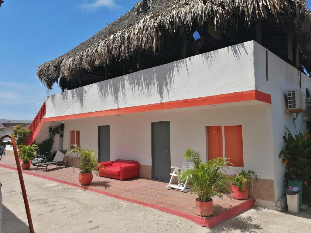 卡塔赫納的住宿－曼薩尼約海灘酒店，一座带红色沙发和稻草屋顶的房子