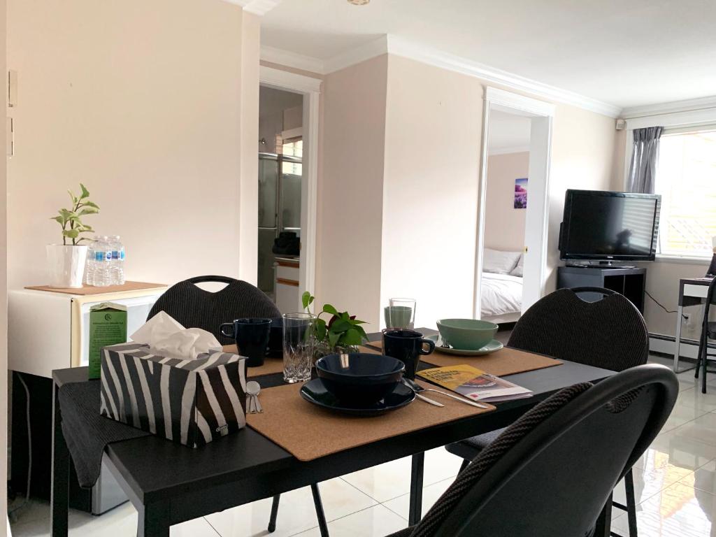 a dining room table with chairs and a table and a television at Perfect Location - Tidy & Comfy Suite 5 Mins to Skytrain & Restaurant & Banks, 2 Stops To Metrotown, 5 Stops To Downtown in Vancouver